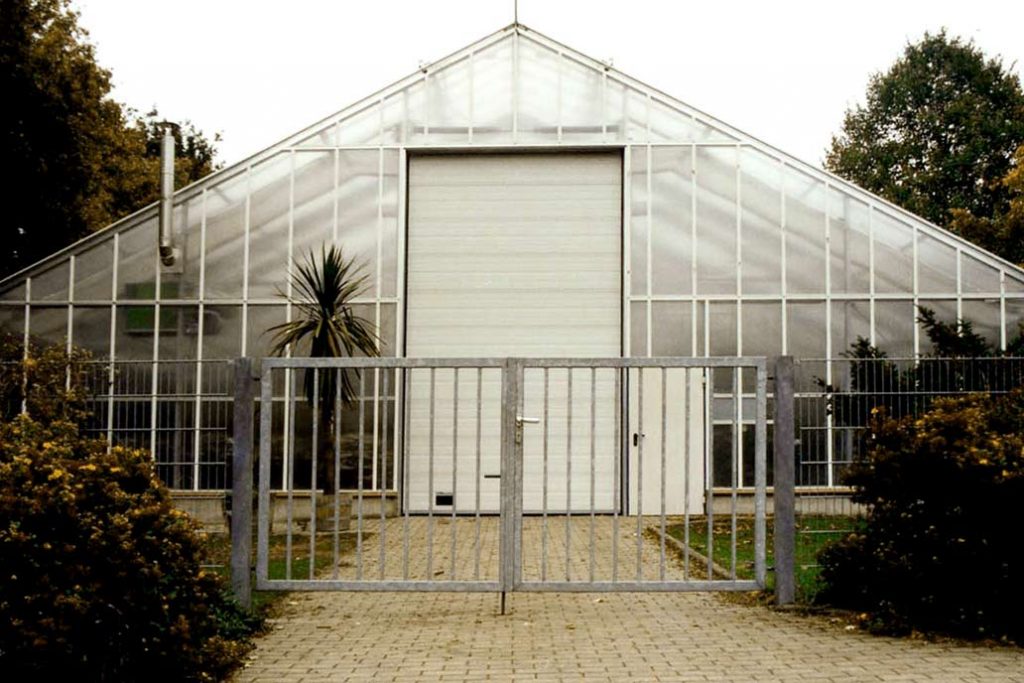 Drehflügeltor aus feuerverzinktem Metall vor einem Gewächshaus in Planten un Blomen Hamburg.
