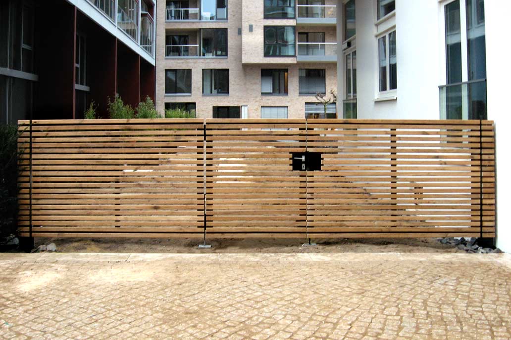 Drehflügeltor aus Metall mit einer blickhemmenden Füllung aus Holzstäben.