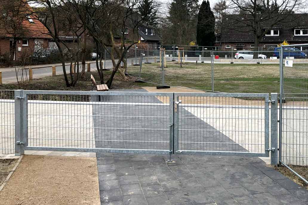 Drehflügeltor mit Stahlmattenfüllung an einem Spielplatz. Die Schenkel des Tors sind unterschiedlich breit. Der kleinere Flügel kann als Tür verwendet werden.